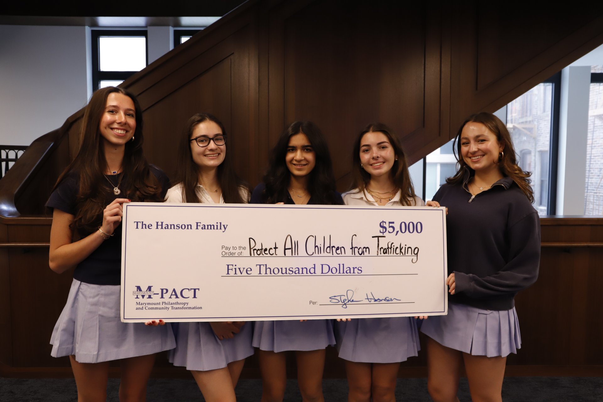 four students holding a donation check from MPACT