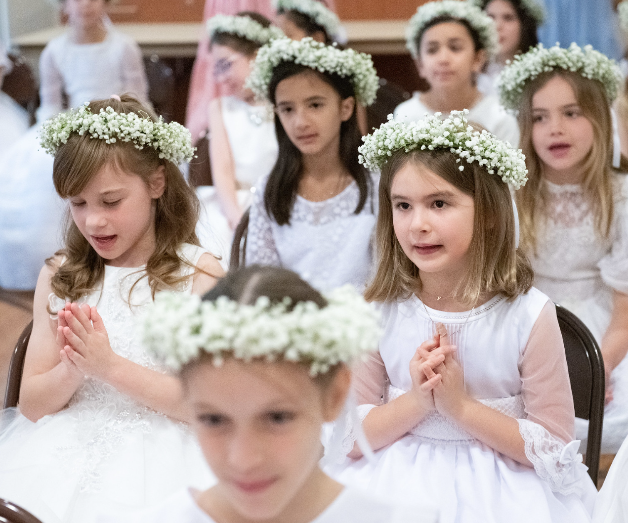 four students in flower crowns and white dresses